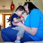 Caitlin Hurley holds her son, Braeden, 3, while the youngster gets a cool drink after playing in the family&rsquo;s home in Gold Bar on Tuesday. Caitlin and her husband, Caleb, adopted Braeden though the National Down Syndrome Adoption Network. The couple hope to adopt another child with Down syndrome. (Dan Bates / The Herald)