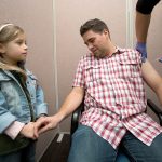 Parker Castano, who admits a fear of needles, has his hand held by his niece, Adeline, 4, as he gets a flu shot at the Everett Clinic on Thursday in Everett. (Andy Bronson / The Herald)