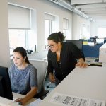 Designer Cristina Kulik works on a computer along with Luisa Rueda, campaign manager at Summa, a company that has migrated to an in-the-moment feedback process. (Darrell Sapp/Pittsburgh Post-Gazette)