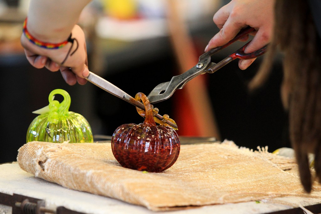 Jo Andersson puts the finishing twist on the stem of a glass pumpkin at the Schack Art Center in Everett. (Ian Terry / The Herald)