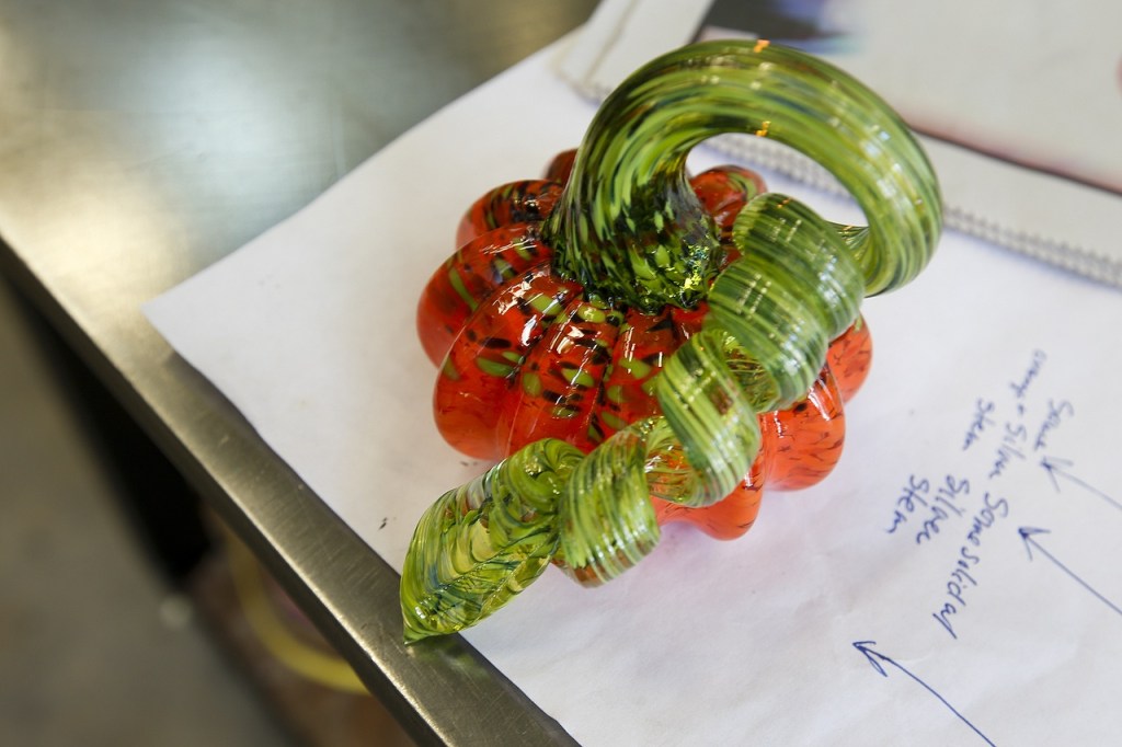 A finished handmade glass pumpkin is seen at the Schack Art Center in Everett. The stem is twisted and rolled in colored glass flakes to create the swirling colors. (Ian Terry / The Herald)