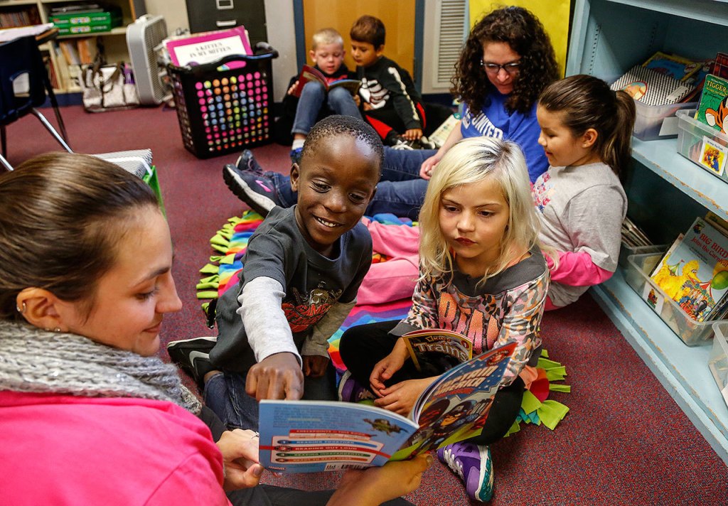 Luhizo Luhizo (front center) enthusicastically points out something in his book, Captain America to the Rescue, for Shelby Spencer (right) while Day of Caring volunteer Megan Hyde (left) pauses reading. Ellen Morehouse (back right) volunteered for the Day of Caring as an individual, and is reading to first-grader Carlie Duenas-Jobsky. In the far back, first-graders Logan Wilkins (left) and Rhidam Acharya enjoy a book on their own. (Dan Bates / The Herald)