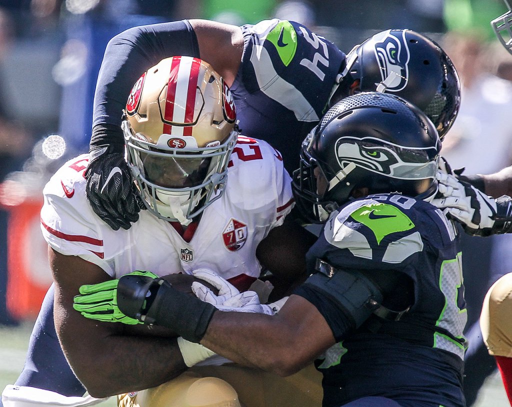 Kevin Clark / The Herald                                49ers running back Carlos Hyde is tackled by Seahawks linebackers Bobby Wagner (top) and K.J. Wright during Sunday&rsquo;s game at CenturyLink Field.