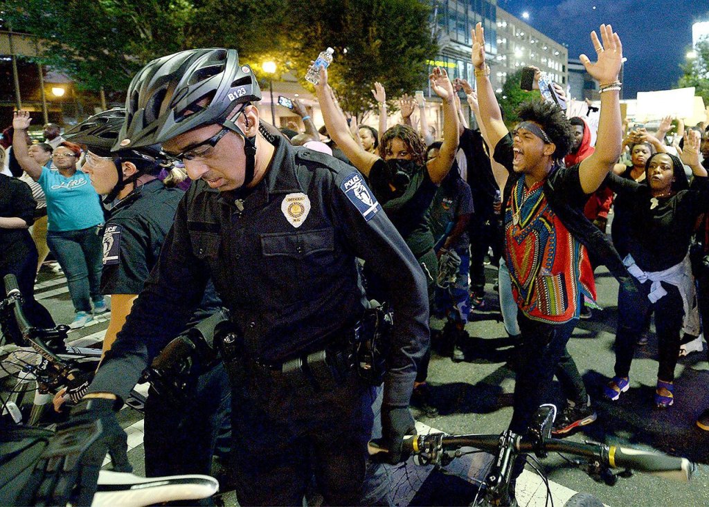 Protesters march behind a bicycle officer along Trade Street in Charlotte, North Carolina, on Wednesday. (Jeff Siner/The Charlotte Observer via AP)