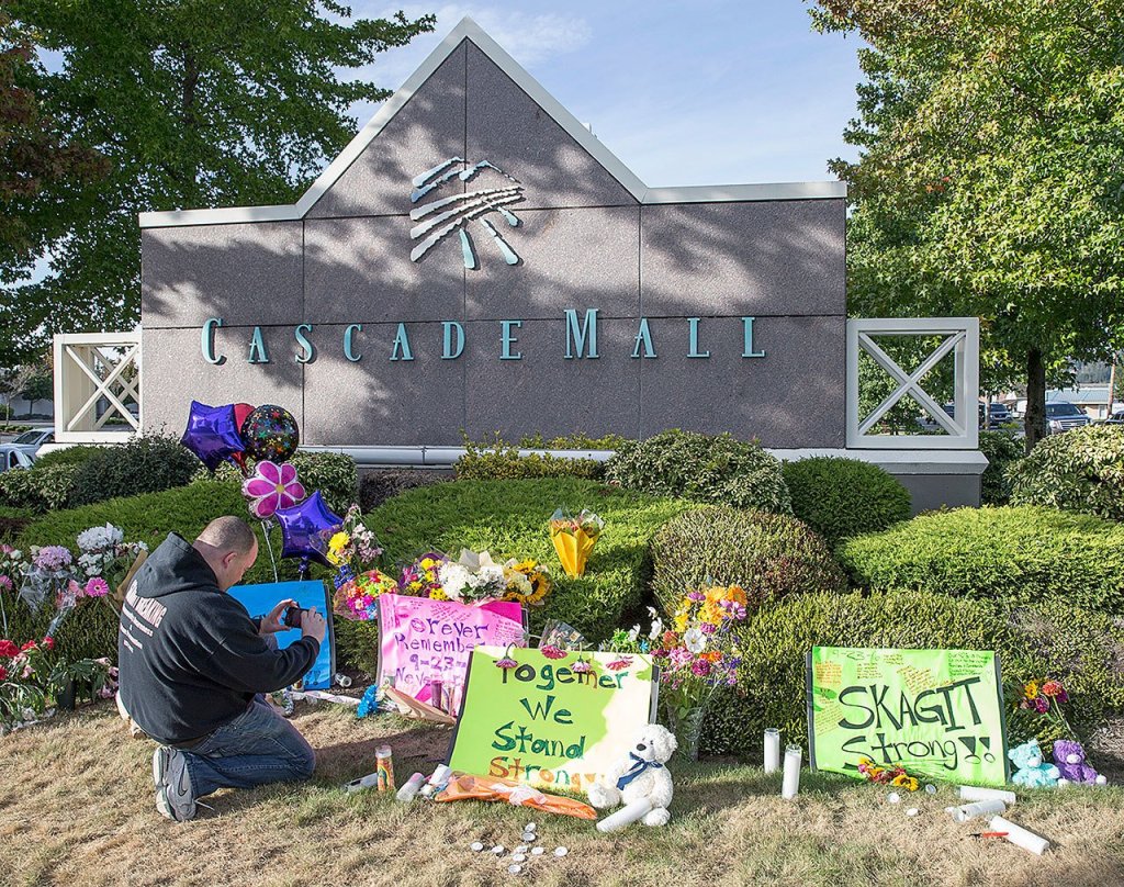 Chris Nelson of Burlington takes a picture of a memorial Sunday, in Burlington, to the five victims killed in Friday&rsquo;s shooting at Cascade Mall. (AP Photo/Stephen Brashear)