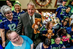 At Shawn O&rsquo;Donnell&rsquo;s, Tuesday night, Snohomish County Sea Hawkers Booster Club members and their president, Nina Therres (left #12) squeeze together with Snohomish County Sheriff Ty Trenary (suit and tie) and a whole bunch of cuddly bears for a photograph. They collected the bears to donate, and Sheriff Trenary will be delivering them to Dawson Place, which serves child victims of sexual or physical abuse. (Dan Bates / The Herald)