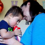 Caitlin Hurley holds her son, Braeden, 3, while the youngster gets a cool drink after playing in the family&rsquo;s home in Gold Bar on Tuesday. Caitlin and her husband, Caleb, adopted Braeden though the National Down Syndrome Adoption Network. The couple hope to adopt another child with Down syndrome. (Dan Bates / The Herald)