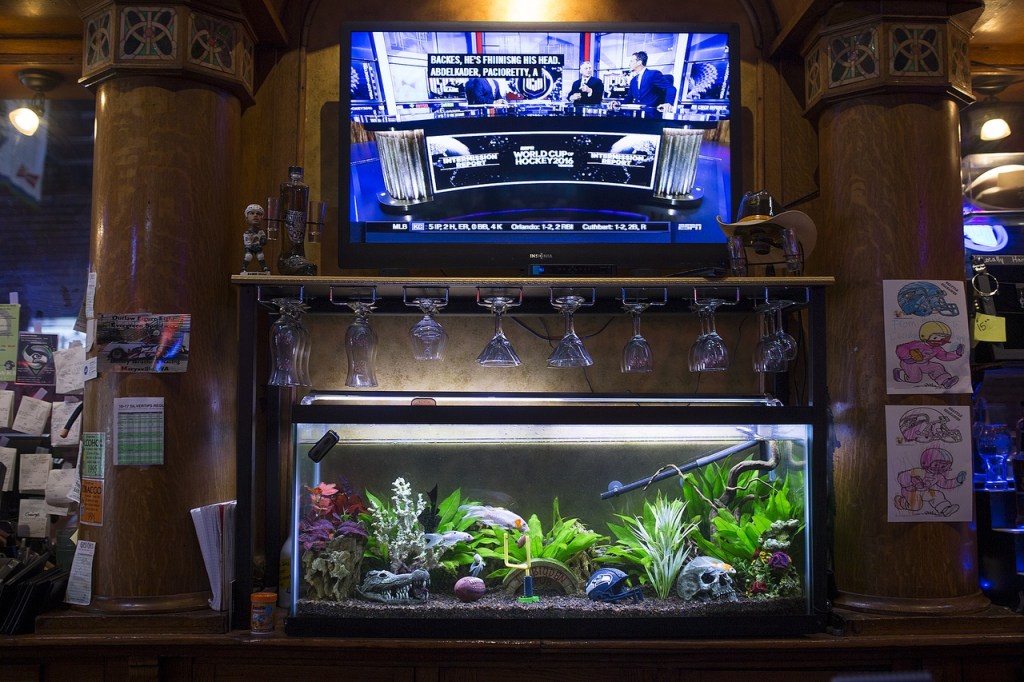 A fish tank and TV screen sit behind the bar at Ynot Sports Pub & Grub in Everett. (Ian Terry / The Herald)