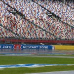 A security guard walks across the track at Charlotte Motor Speedway in Charlotte, N.C., Friday. NASCAR activities at the track were cancelled for the day due to weather. (AP Photo/Chuck Burton)