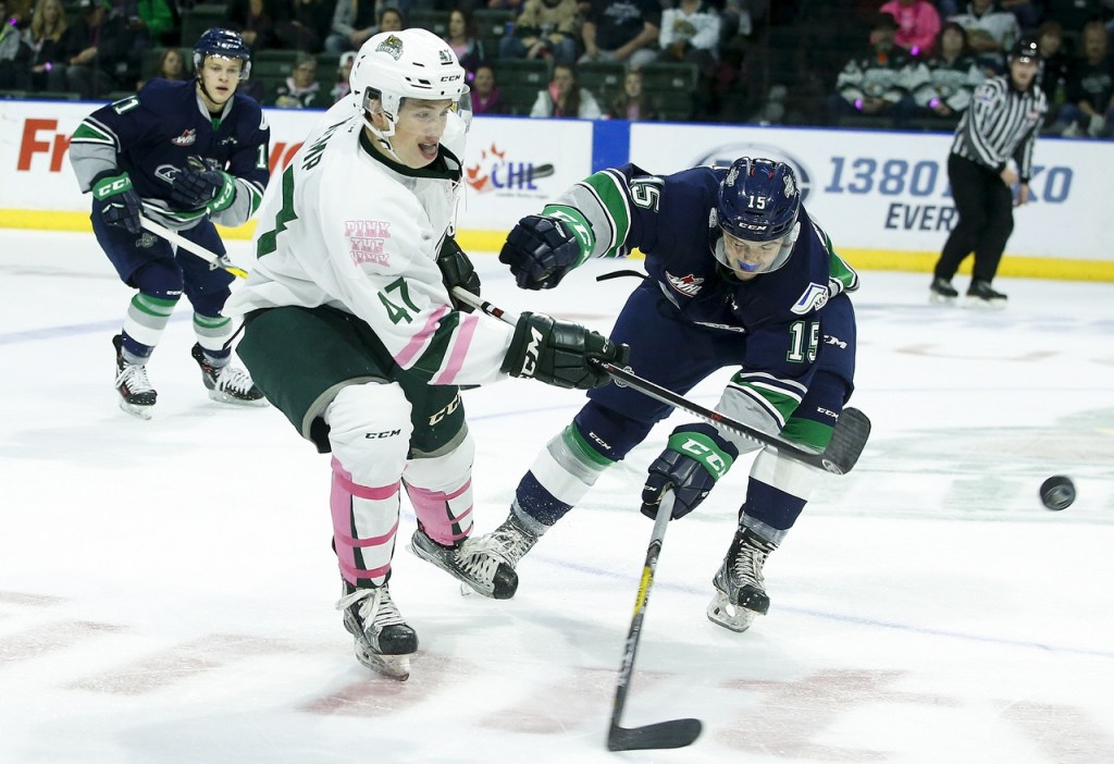 Silvertips center Brett Kemp (47) battles for a loose puck with Thunderbirds right wing Layne Bensmiller (15) during a game Saturday at Xfinity Arena in Everett. (Ian Terry / The Herald)
