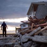 A police officer steps over the remnants of a home leveled by Hurricane Matthew after it hit the tiny beach community of Edisto Beach, South Carolina, on Saturday. (AP Photo/David Goldman)
