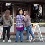Laina Lundgren, right, puts a hand on the shoulder of 2 Bits and More owner Dawn Ambler as they look over the remains of the indoor flea market and thrift shop after a fire the night before on Tuesday, Oct. 25, 2016 in Arlington, Wa. At left is Ambler&rsquo;s niece Jeness Crtiz. (Andy Bronson / The Herald)