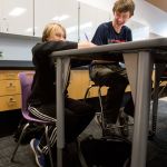 Leota Junior High eighth graders Elliott Tobin (left) and Jake Mullins laugh as they test out different chairs and desks at North Creek High School on Wednesday in Bothell. The students tested and graded three different sets of chairs and desks that the Northshore School District may purchase for the new high school. (Andy Bronson / The Herald)