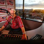 Stitch Mitchell enjoys a sunrise at his back as he hosts the KKXA-AM morning show Wednesday from the 14th floor of the Everett Mutual Tower on Colby. (Dan Bates / The Herald)