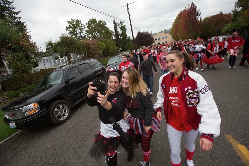 A trio of Snohomish High School students take a selfie as they walk in Friday&rsquo;s annual Serpentine Parade, a tradition for generations of students in Snohomish. (Andy Bronson / The Herald)