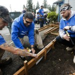 Volunteers (from left) Joseph Thomas, Ernest Juarez and Allen Everson help build a new ramp up to Faith Lutheran Church&rsquo;s food bank in Everett on Oct. 8. More than two dozen volunteers pitched in to replace old stairs with a ramp that will allow for easier deliveries of goods to the food bank. (Ian Terry / The Herald)