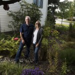 Paul and Roxanne Wright stand in their rain garden at their home in Everett. The garden, designed by Roxanne, is recessed three feet into the earth and draws water from pipes along the roof. (Ian Terry / The Herald)