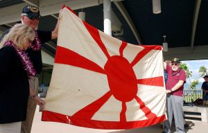 Dianne Hall helps hold up the Japanese navy flag during a ceremony at Pearl Harbor, Hawaii, on Thursday. (AP Photo/Jennifer Kelleher)