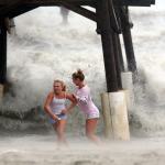 Kaleigh Black (left), 14, and Amber Olsen, 12, run for cover as a squall with rain and wind from the remnants of Hurricane Matthew pelt them at the Cocoa Beach Pier on Friday in Cocoa Beach, Florida. (Douglas R. Clifford/Tampa Bay Times via AP)