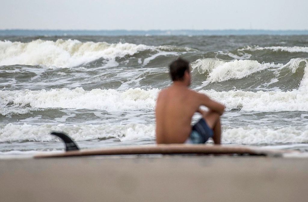 Eric Dunn sits on the beach on Tybee Island, Georgia, on Tuesday, watching larger-than-normal waves roll in as a result of approaching Hurricane Matthew. (Josh Galemore/Savannah Morning News via AP)