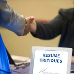 A job seeker stops at a table offering resume critiques during a job fair in Atlanta in 2013. (AP Photo/John Amis)