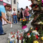 People gather at makeshift memorial at a tour bus stop in Los Angeles on Monday, Oct 24. The National Transportation Safety Board said the tour bus, which crashed and left 13 dead and 31 injured near Palm Springs, in California, had 2 faulty tires. (AP Photo/Damian Dovarganes)
