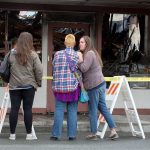 Laina Lundgren (right) puts a hand on the shoulder of 2 Bits and More owner Dawn Ambler as they look over the remains of the indoor flea market and thrift shop after a fire the night before on Tuesday in Arlington. At left is Ambler&rsquo;s niece, Jeness Crtiz. (Andy Bronson / The Herald)