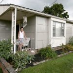 Sue Williams stands on the front porch of her Lustron home in Canton, Ohio. The prefab steel house was made in 1950 by the Lustron Corp. of Columbus. (Michael Chritton/Akron Beacon Journal)