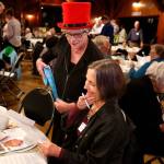 In the bright red top hat, Cyndie Henderson is 10 seconds away from convincing Nancy Lombard of Snohomish to buy some raffle tickets Wednesday night at the Interfaith Fundraiser in Everett. Lombard bought $20 worth of the tickets. (Dan Bates / The Herald)