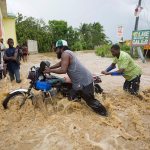 Men push a motorbike through a street flooded by a river that overflowed from heavy rains caused by Hurricane Matthew in Leogane, Haiti, on Wednesday. Rescue workers in Haiti struggled to reach cutoff towns and learn the full extent of the death and destruction caused by Hurricane Matthew as the storm began battering the Bahamas on Wednesday and triggered large-scale evacuations along the U.S. East Coast. (AP Photo/Dieu Nalio Chery)