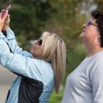 Lila Davenport takes a photo while she and Becky Reimer watch as a great horned owl is rescued at the Everett Marina on Wednesday in Everett. (Andy Bronson / The Herald)