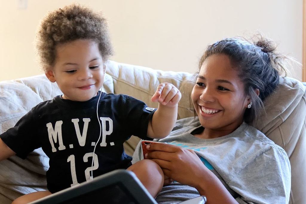 DeJohn Ward-Taylor, &ldquo;Little DJ,&rdquo; bops to music in the lap of his aunt, Veronika Taylor, at their home in Marysville. Little DJ lost his father to suicide four months before he was born. (Kevin Clark / The Herald)