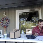 Blake Halsey, a 21-year-old college student and volunteer at the Orange County GOP office, takes a phone call from someone offering to volunteer Monday in Hillsborough, North Carolina. Halsey sits under the window where authorities say someone threw in a flammable device that burned the campaign office. (AP Photo/Jonathan Drew)