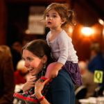 Oh, what a night! Cathy Merchant of Redmond carries her 2-year-old daughter Inara on her shoulders as she negotiates a big crowd during a beautiful evening at Forest Park&rsquo;s Floral Hall while attending a fundraiser for the Interfaith Association&rsquo;s family shelter Wednesday. (Dan Bates / The Herald)