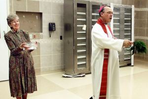 Sister Dorothy Klingele assists then-Seattle Archbishop Alexander Brunett with holy water during a 2002 blessing of an operating room in the Family Maternity Center at Providence Regional Medical Center Everett&rsquo;s Pavilion for Women and Children. Klingele, who served in health care with the Sisters of Providence for decades, died Oct. 15 at age 90. (Stephanie S. Cordle/Herald File)