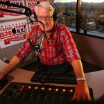 Stitch Mitchell enjoys a sunrise at his back as he hosts the KKXA-AM morning show Wednesday from the 14th floor of the Everett Mutual Tower on Colby. (Dan Bates / The Herald)