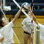 Arlington players Mary Catherine Meno (left) and Madison Culhane (right) both get a hand on a ball near the net during a team practice at the school on Wednesday. (Ian Terry / The Herald)
