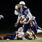 Meadowdale quarterback Drew Tingstad fumbles as he&rsquo;s hit by Kelso defenders during a first round 3A state playoff game Friday at Edmonds. (Ian Terry / The Herald)