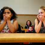 Kortnei, 9 (left) and Miah Schramm, 8, can hardly conceal their delight as they sit down at a big table facing Judge David A. Kurtz on Friday in Snohomish County Superior Court. The two young girls not only scored a mom and a dad on National Adoption Day, but also landed each other. Sisters! (Dan Bates / The Herald)
