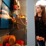 Darby Kelly, 7, niece of the Edmonds Historical Museum Director, Caitlin Kelly, explores display cases filled with very old play things that make up the current holiday exhibit &ldquo;Once Upon a Toy.&rdquo; (Dan Bates / The Herald)