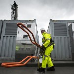 Alex Weenink, lead field technician for the Snohomish County Public Utility District, carries a ladder after his crew finished hoisting 20 new vanadium flow batteries into place at the Everett Substation on Wednesday. Mukilteo-based UniEnergy Technologies made the units, which will allow for the PUD to better handle peak usage by storing energy in the big batteries. (Ian Terry / The Herald)