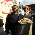 Kevin Hughes stands near the Yummy Box Food Truck after picking up his order of chicken stir fry on Friday afternoon in Everett. &ldquo;I got off the bus and my nose led me here,&rdquo; Hughes said. Three Snohomish County-based food trucks will share a space near the Everett Performing Arts Center each Friday at lunch time as part of a year-long pilot project with the city. (Ian Terry / The Herald)