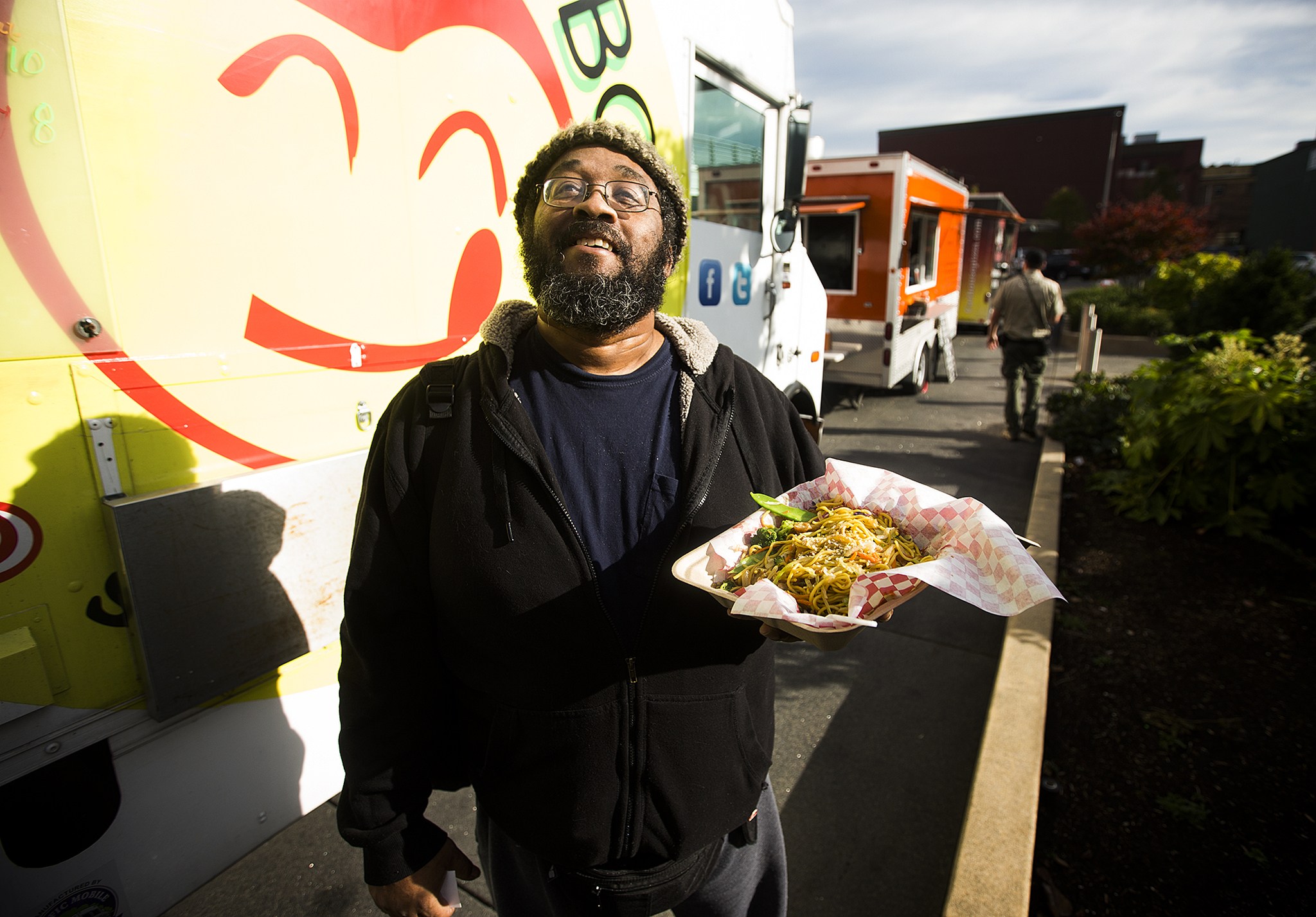 Kevin Hughes stands near the Yummy Box Food Truck after picking up his order of chicken stir fry on Friday afternoon in Everett. &ldquo;I got off the bus and my nose led me here,&rdquo; Hughes said. Three Snohomish County-based food trucks will share a space near the Everett Performing Arts Center each Friday at lunch time as part of a year-long pilot project with the city. (Ian Terry / The Herald)