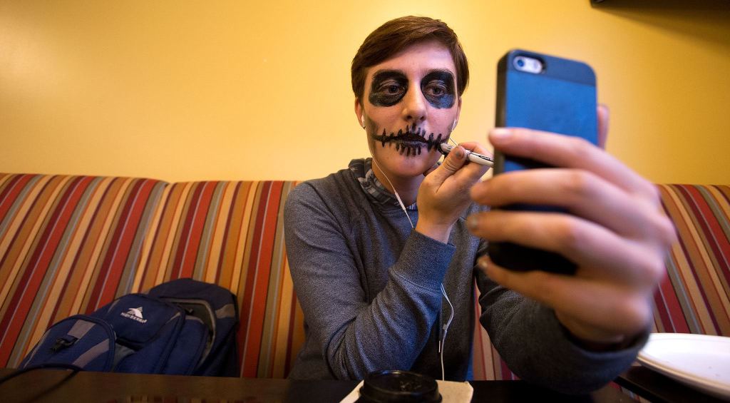 Amanda Brown, 17, from Lakewood High School, applies makeup, using her cellphone as a mirror, as other students and faculty compete in the Hallo-Scream Contest at Everett Community College on Monday. (Andy Bronson / The Herald)