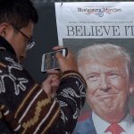 Zheng Gao of Shanghi, China, photographs the front pages of newspapers on display outside the Newseum in Washington the day after Donald Trump won the presidency on Nov. 9. (AP Photo/Susan Walsh)