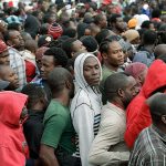 In this Oct. 3 photo, Haitians line up at an immigration agency in Tijuana, Mexico, with the hope of gaining an appointment to cross to the U.S. side of the border. A surge in border crossings and a lack of immigration jail space have prompted the federal government to start releasing Haitian immigrants who have been entering the country in large numbers in recent months, backtracking on a pledge to jail the migrants. (AP Photo/Gregory Bull, File)