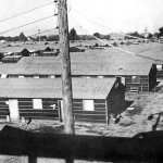 In this undated photo provided by the War Relocation Authority, armed guard overlooks barracks built in the middle of the racetrack at the Fresno Fairgrounds in Fresno, California. The assembly center, one of 13 built in California, was the first stop for detainees before they were sent to permanent internment camps. About 5,300 people were held at the center between May and October 1942. (AP photo/War Relocation Authority)