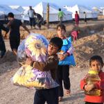 Displaced Iraqi boys, who fled from Mosul with their families, carry food and other aid supplies at a camp for internally displaced people in Hassan Sham, east of Mosul, Iraq, on Saturday, Nov. 12. (AP Photo/Hussein Malla)