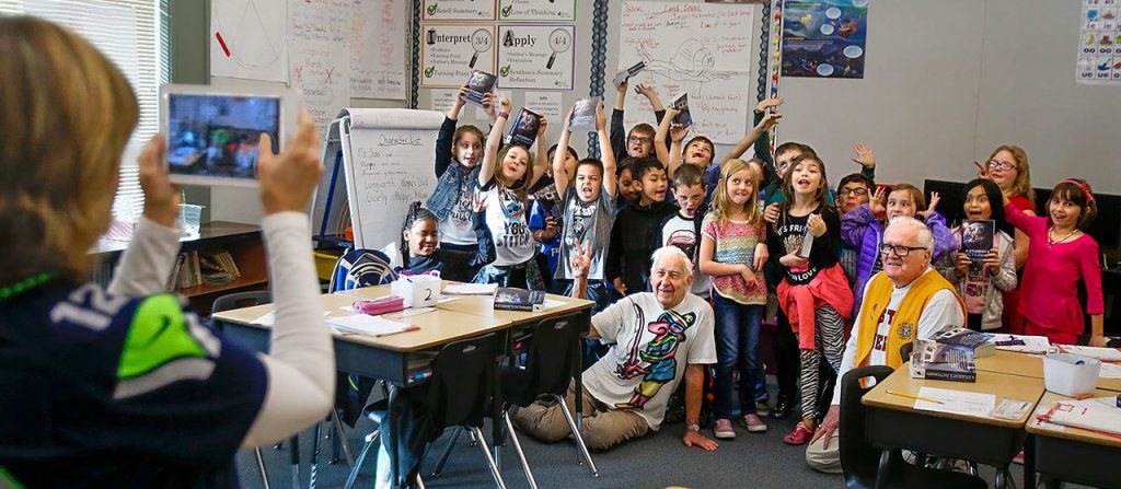 Kiwanis Club volunteers Jack Lapoint (center floor) and James Henry (right) pose with third-graders for teacher Christi Castro to photograph after giving the kids new dictionaries from the Kiwanis Club for the last time. (Dan Bates / The Herald)