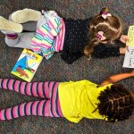 Mercy Mathews (bottom) and Lily Holt get comfortable and start reading the new books. (Dan Bates / The Herald)